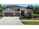Charming two-story home featuring a well-manicured lawn, a three-car garage, and stone accents at 15625 Hawks Crest Loop, Odessa, FL 33556