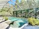 Beautiful pool surrounded by lush greenery, enclosed by a screen for privacy and enjoyment, and lovely stone tiling at 15625 Hawks Crest Loop, Odessa, FL 33556