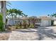 Charming single-story home featuring a two-car garage, lush landscaping, and a brick-paved driveway at 16353 Redington Dr, Redington Beach, FL 33708