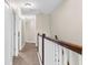 Bright hallway with carpet, white doors, and wood railing leading upstairs at 1969 Milkweed Trce, Lutz, FL 33558