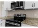 Close-up of a kitchen cooktop with stainless steel microwave and granite countertop, offering a sleek and modern design at 1969 Milkweed Trce, Lutz, FL 33558