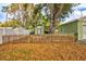 Fenced backyard with green house and mature trees provides a private outdoor space at 1984 Trotter Rd, Largo, FL 33774
