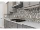 Close-up of a well-equipped kitchen with gray cabinets, a gas cooktop, and a stylish backsplash at 21878 Amelia Rose Way, Land O Lakes, FL 34637