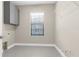 Bright laundry room features gray cabinets, window and gray tile flooring at 21878 Amelia Rose Way, Land O Lakes, FL 34637