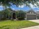 Charming single-story home with a well-manicured lawn and beautiful palm trees under a partially cloudy sky at 2603 Valencia Grove Dr, Valrico, FL 33596