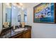 A well-lit half bathroom with a granite countertop and decorative painting at 2674 Tanglewood Trl, Palm Harbor, FL 34685