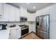 A modern kitchen with white cabinets, stainless steel appliances, and light-colored backsplash at 2674 Tanglewood Trl, Palm Harbor, FL 34685