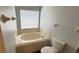 A clean and tidy bathroom with a soaking tub beneath the window at 28818 Midnight Star Loop, Wesley Chapel, FL 33543