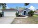 Charming single-story home with blue exterior, landscaped front yard, and attached two-car garage at 28818 Midnight Star Loop, Wesley Chapel, FL 33543