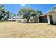 Large backyard and home exterior with mature trees shading the grassy lawn at 3114 Little Rd, Valrico, FL 33596