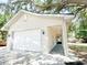 Exterior of garage, with white siding, concrete driveway, and landscaping with large oak tree at 3114 Little Rd, Valrico, FL 33596