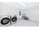 Bright laundry room with modern washer and dryer set, shelving, window, and neutral color palette at 3114 Little Rd, Valrico, FL 33596