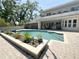 Backyard in-ground pool surrounded by brick paver deck, lounge area, and flower bed at 3114 Little Rd, Valrico, FL 33596