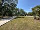 Manicured lawn with shady trees, and a landscaped walkway with a concrete path at 3114 Little Rd, Valrico, FL 33596
