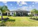 Beautiful backyard with a screened-in lanai, lush green lawn, and tropical landscaping at 31637 Cannon Rush Dr, San Antonio, FL 33576