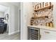 Stylish bar area featuring a wine fridge, wine rack, and decorative wallpaper with wooden shelves at 31637 Cannon Rush Dr, San Antonio, FL 33576