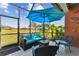 Relaxing screened patio with seating and a view of the pond, and tropical landscaping at 31637 Cannon Rush Dr, San Antonio, FL 33576