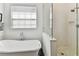 Elegant bathroom features a soaking tub, a glass shower with herringbone tile, and a large window at 3311 Home Ct, Tampa, FL 33611