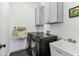 Laundry room with washer, dryer, utility sink, gray cabinets, and sleek black hexagonal tile flooring at 3311 Home Ct, Tampa, FL 33611