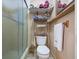 Cozy bathroom with a shower, toilet, and shelving unit for storing towels and toiletries at 3338 Hoover Dr, Holiday, FL 34691