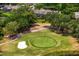Overhead shot of a pristine golf course featuring a green, a sand trap, and lush landscaping near residences at 4240 Golf Club Ln, Tampa, FL 33618