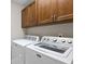 This laundry room features a white washer and dryer set with wooden cabinets above at 4240 Golf Club Ln, Tampa, FL 33618