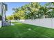 Expansive backyard with lush artificial grass, complemented by tall trees and a secure white fence at 481 W Davis Blvd, Tampa, FL 33606