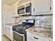 Well-equipped kitchen featuring modern appliances, white cabinets, and granite countertops, providing a functional cooking space at 5227 81St Lane N # 26, St Petersburg, FL 33709