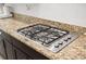 Close up of a gas cooktop on a stone countertop with dark cabinets at 5310 Sanderling Ridge Dr, Lithia, FL 33547