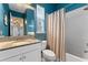 Bright blue bathroom featuring a granite countertop vanity and a tub with shower curtain at 5903 Nature Ridge Ln, Lithia, FL 33547