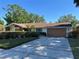 Charming single-story home with a well-kept lawn, a two-car garage, and stone architectural details at 6703 Peachtree Dr, Temple Terrace, FL 33617