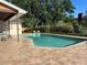 Backyard pool with brick patio, surrounded by lush greenery and a charming garden at 6703 Peachtree Dr, Temple Terrace, FL 33617