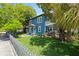 Beautiful exterior view of a blue two-story home, surrounded by lush greenery and a white picket fence at 701 14Th N St, St Petersburg, FL 33705