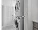 Laundry area with stacked washer and dryer, mosaic-style tiled wall, and black and white tiled floors at 701 14Th N St, St Petersburg, FL 33705