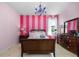 A pink bedroom with striped accent wall, chandelier, dark wood furniture and light tile flooring at 706 S Davis Blvd, Tampa, FL 33606