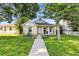 Inviting front exterior featuring a covered porch, lush green lawn, and well-maintained landscaping at 718 30Th N Ave, St Petersburg, FL 33704