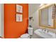 Stylish powder room features an orange accent wall and elegant pedestal sink at 729 Manns Harbor Drive, Apollo Beach, FL 33572