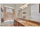 Bathroom with granite countertop, framed mirror, and a bathtub with glass doors at 729 Manns Harbor Drive, Apollo Beach, FL 33572