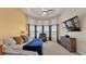 Comfortable main bedroom featuring a cozy chair, tray ceiling, and a TV at 729 Manns Harbor Drive, Apollo Beach, FL 33572