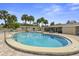 A stunning in-ground swimming pool offers a refreshing escape under clear blue skies, surrounded by comfortable seating and lush greenery at 834 Cambridge Ct, Dunedin, FL 34698