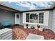 Covered entryway featuring tiled path, white door, large picture window and bench at 8413 Moulton Dr, Port Richey, FL 34668