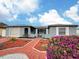 Charming single-story home with attached garage, a red brick walkway and lovely landscaping at 8413 Moulton Dr, Port Richey, FL 34668