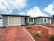 Single-story home with attached garage, a red driveway and decorative mulch landscaping at 8413 Moulton Dr, Port Richey, FL 34668