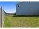 View of the backyard with grass, a partial view of the home, and a white fence at 10749 Tally Fawn Loop, San Antonio, FL 33576