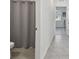 Hallway with view into bathroom featuring granite countertop vanity, toilet, and shower with a gray shower curtain at 10749 Tally Fawn Loop, San Antonio, FL 33576