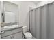 Well-lit bathroom featuring a granite countertop vanity, toilet, and shower with a gray shower curtain at 10749 Tally Fawn Loop, San Antonio, FL 33576