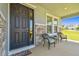 Inviting front porch featuring a stylish front door, decorative stone accents, and cozy wicker seating at 10749 Tally Fawn Loop, San Antonio, FL 33576