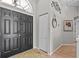 Welcoming foyer with stylish black entry door, closet, decorative mirror and art, and neutral tile flooring at 1077 Captains Way, Tarpon Springs, FL 34689