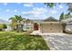 Charming single-story home features a manicured lawn, two-car garage, and vibrant red front door at 1077 Captains Way, Tarpon Springs, FL 34689