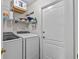 Efficient laundry room with washer, dryer, shelving, and a white door at 1077 Captains Way, Tarpon Springs, FL 34689